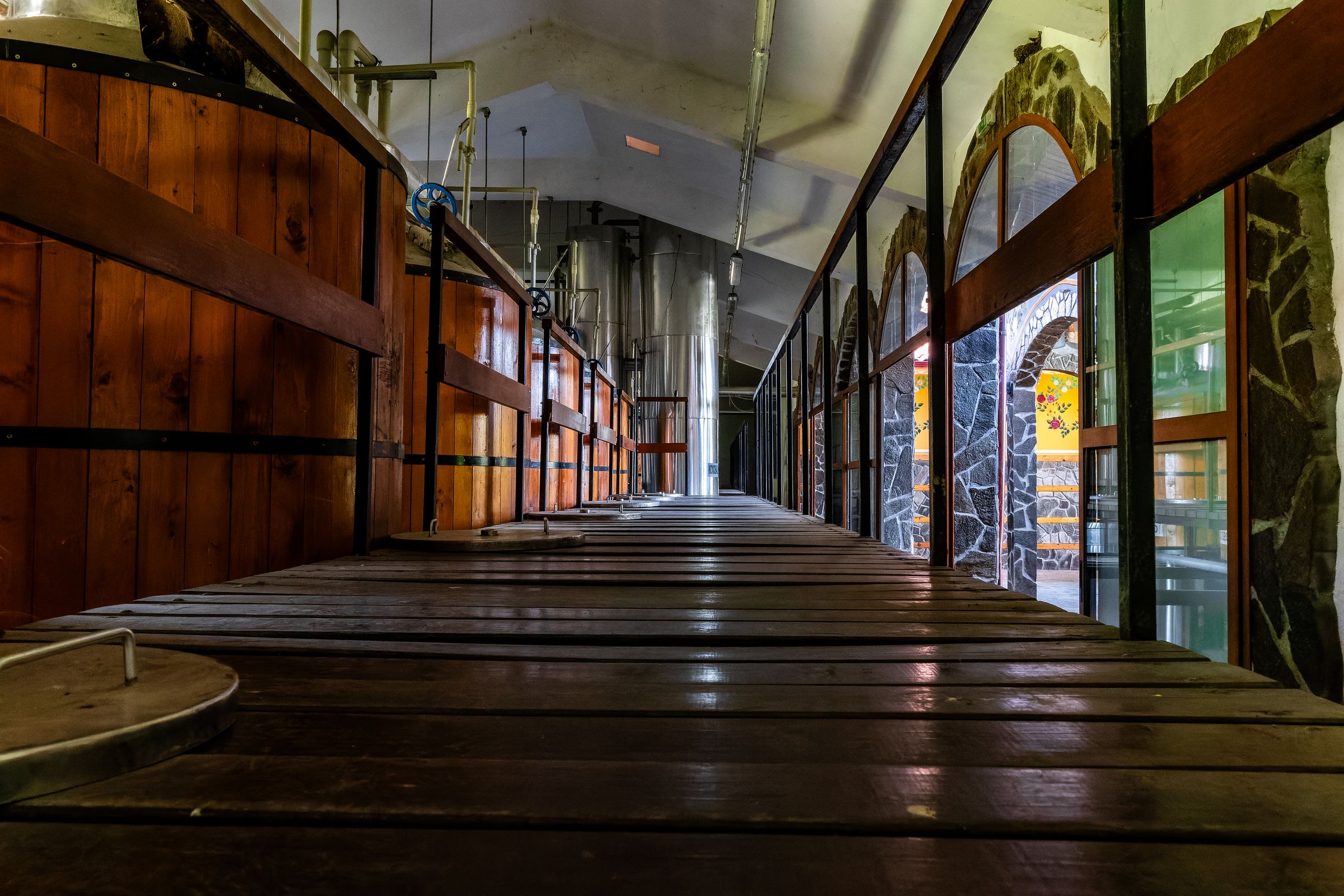 Houten gistkuipen langs een loopbrug in een oude brouwerij.